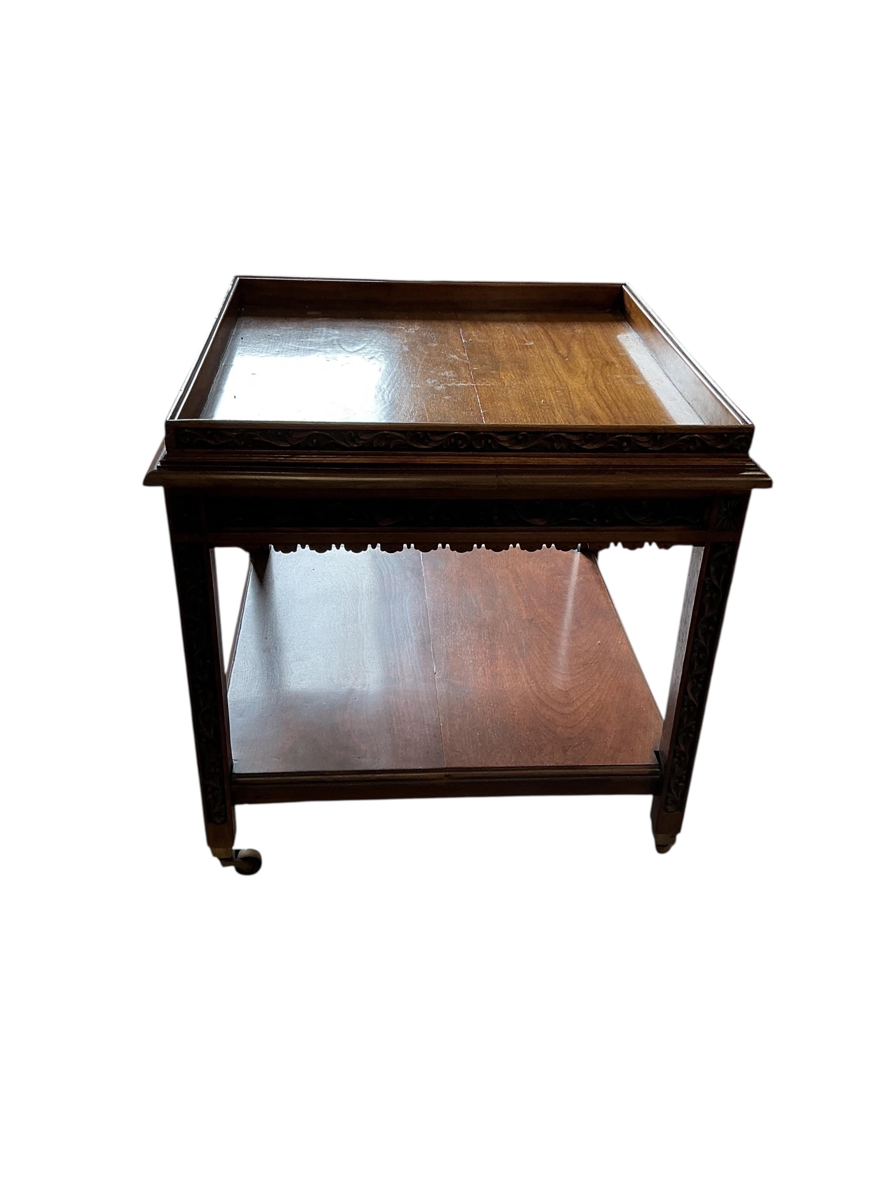 An early 20th century carved walnut square two tier occasional table, with brass caps and casters, 76cm, height 76cm